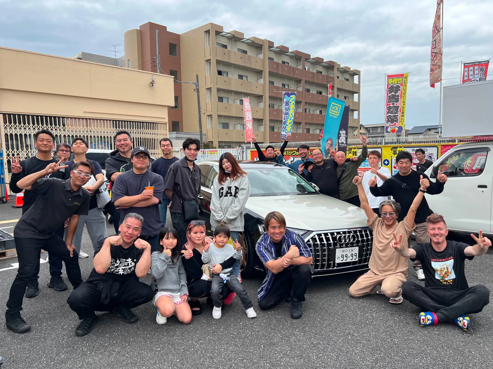 車を囲んで集まるイベント参加者の集合写真